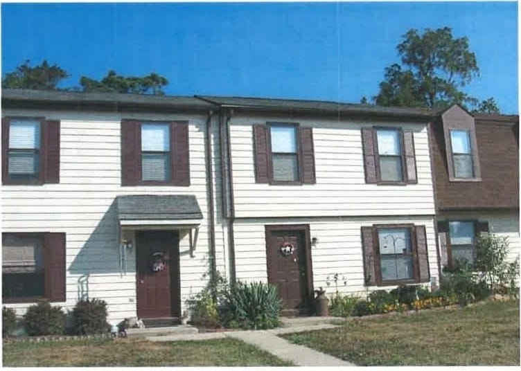 White Thurmont Village townhouses with brown shutters and doors under a clear blue sky