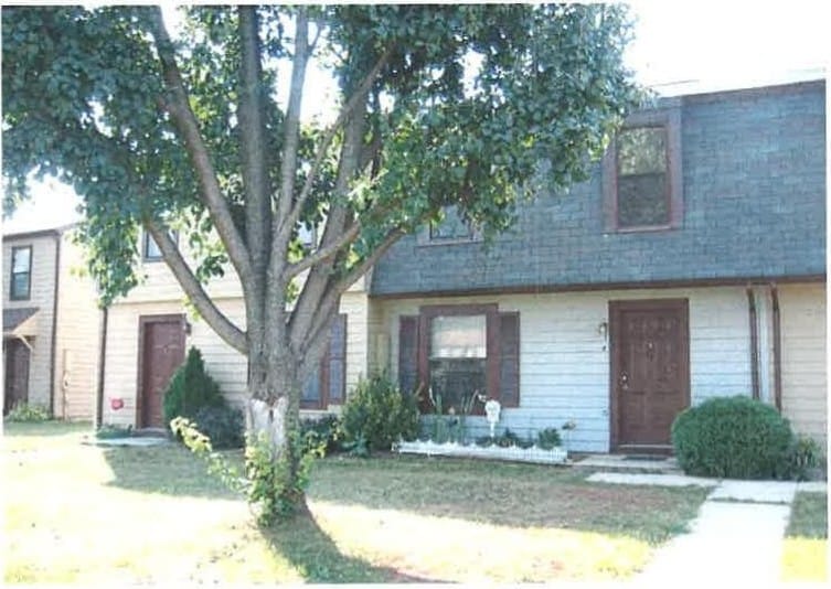 Two-story Thurmont Village townhouses with light siding and a mature tree on the front lawn