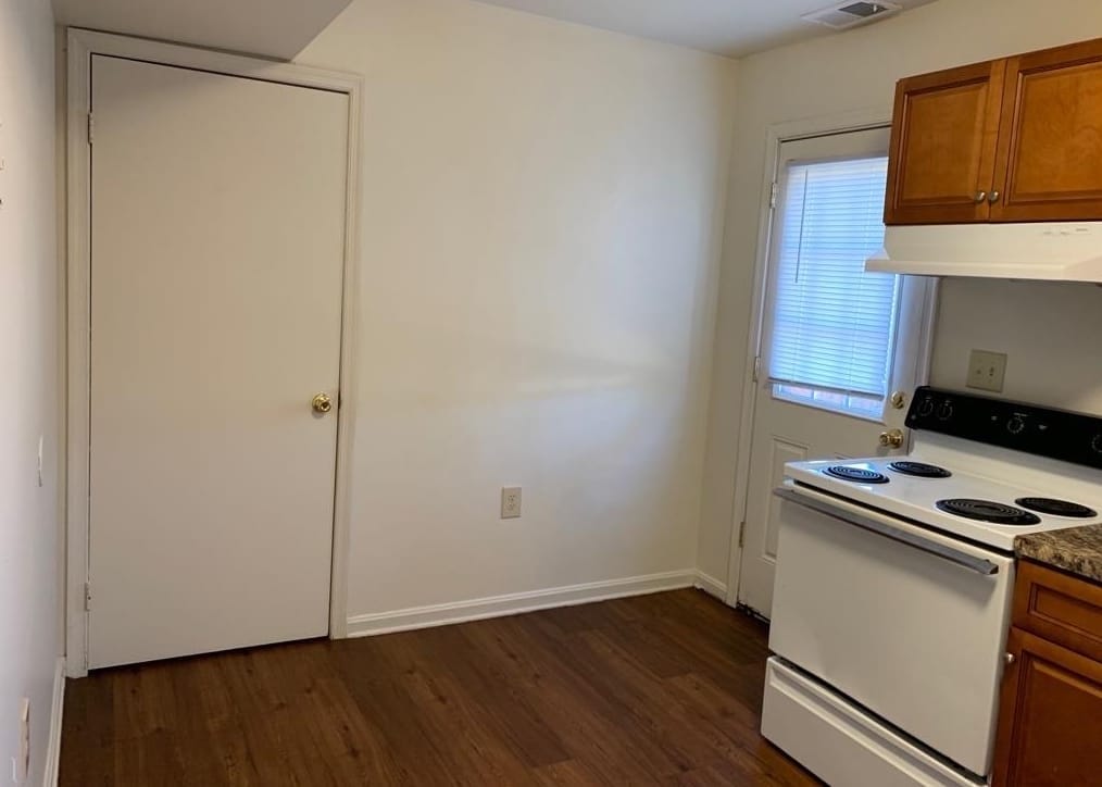 A Thurmont Village kitchen with a white electric range and vent hood beside a back door, with room for a table