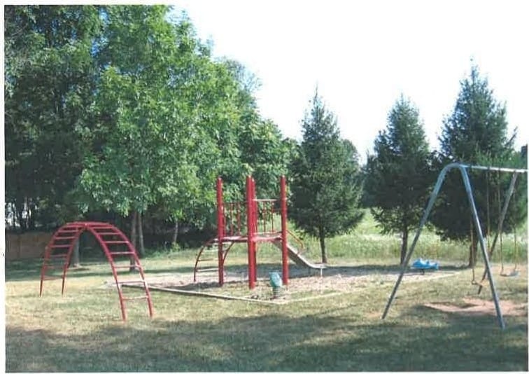 The community playground at Thurmont Village, with a slide, climbing frame, and swings at the edge of the trees
